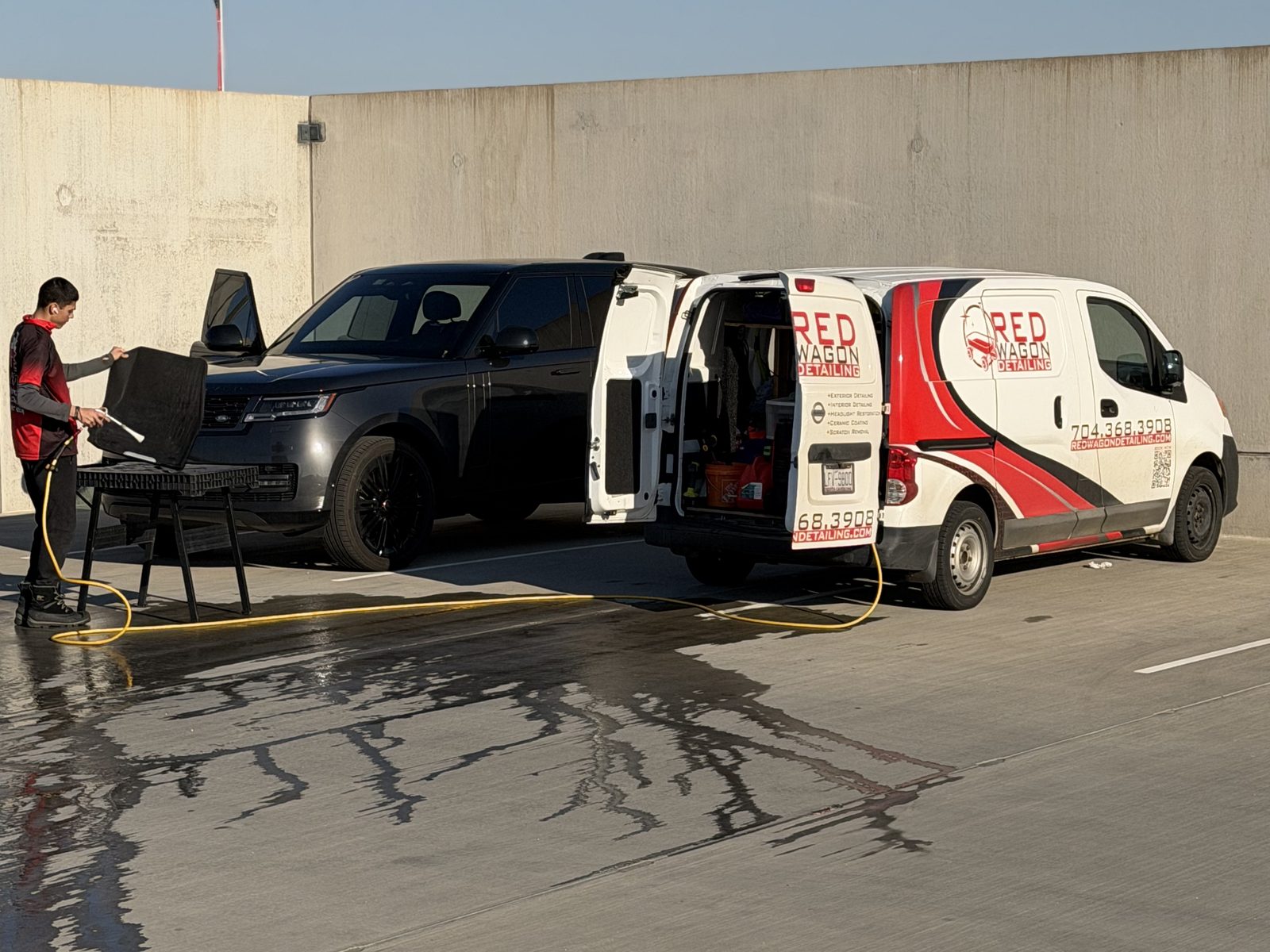 Red Wagon Detailing mobile van and setup detailing a black SUV on site