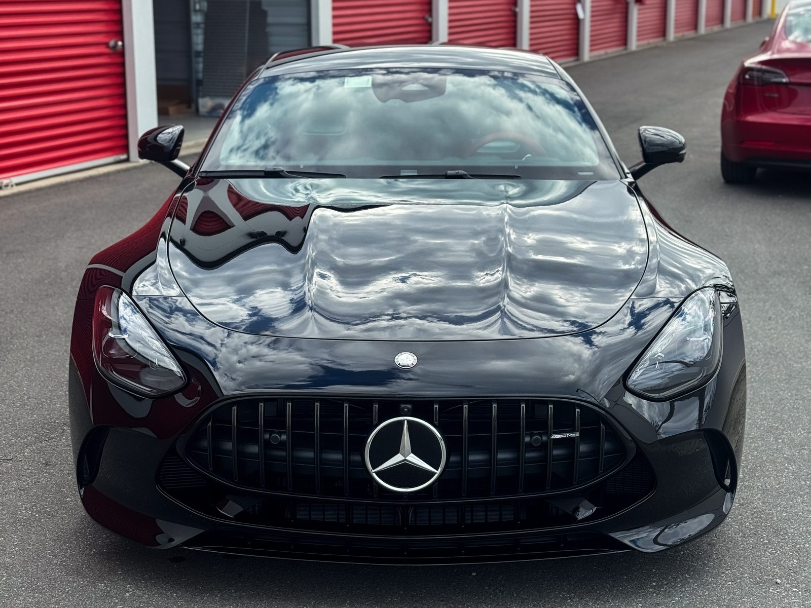 Glossy black Mercedes-AMG coupe outside red storage doors, Red Wagon Detailing Charlotte NC